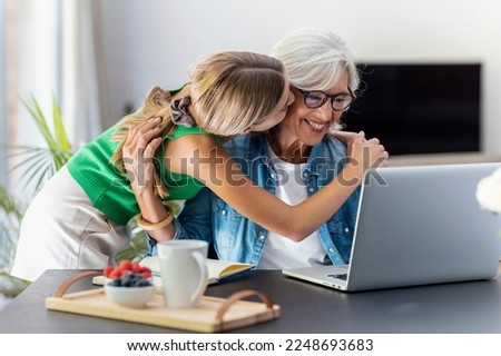 Shot of happy granmother using laptop with her granddaughter at home.
