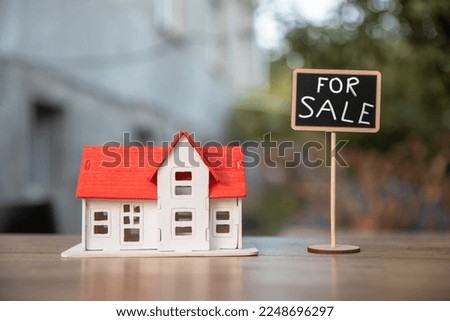 Small house with a sign for sale on the table
