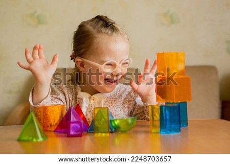 A girl with Down's syndrome lays out geometric shapes Royalty-Free Stock Photo #2248703657
