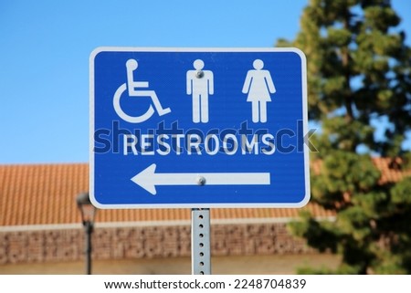 Restrooms. Bathroom Sign. Handicap, Men and Women Restrooms Sign. Restrooms to the left. Public Toilets. Blue Metal Sign on a metal post. Public Restrooms. 