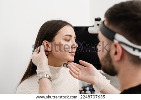 Otoplasty ear surgery. Surgeon doctor examines girl ears before otoplasty cosmetic surgery. Otoplasty surgical reshaping of pinna and ear Royalty-Free Stock Photo #2248707635
