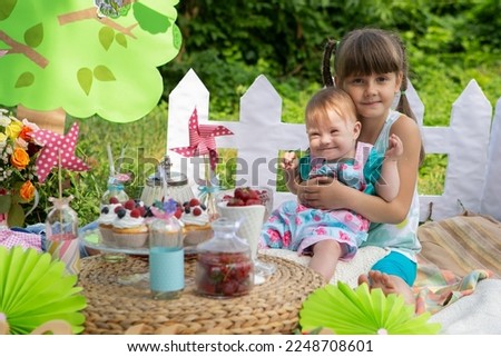Portrait of a beautiful girl with a lovely little sister with Down syndrome in the park