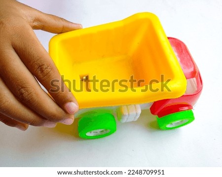 Close up of kid hand playing colorful sand truck toy on white background