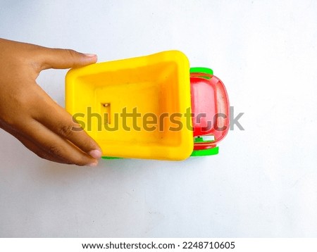 Top view of kid hand playing colorfull sand truck toy on white background