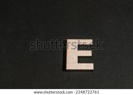 Letter E in wood on black background