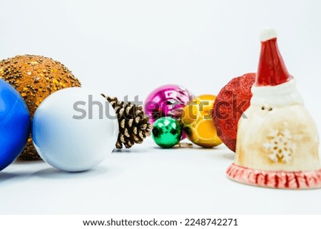 Colorful christmas tree balls on white background with Santa Claus statuette.