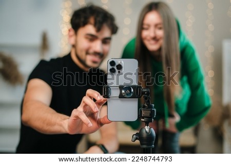 Smiling young couple with happy faces looking at phone camera, bloggers recording videoblog at home. Video live streaming. Royalty-Free Stock Photo #2248744793