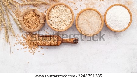 Wheat grains , brown wheat flour and white wheat flour in wooden bowl set up on white concrete background. Royalty-Free Stock Photo #2248751385