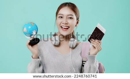 Happy Asian teen girl student shows passport ticket isolated on plain mint green background. Tourist travel high school study abroad getaway Air flight concept.