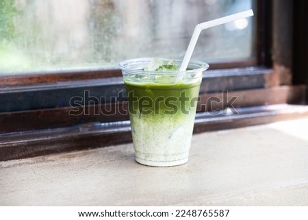 Close up glass of Iced Green Tea Latte placed on an old cement floor
