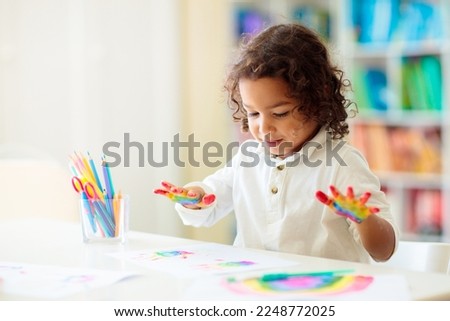 Child drawing rainbow. Paint on hands. Remote learning and online school art homework from home. Arts and crafts for kids. Little boy drawing bright picture. Creative kid playing and studying.