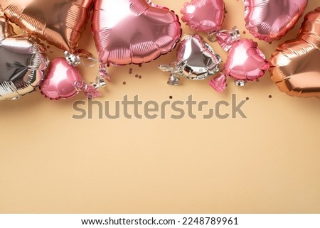 Top view photo of Valentine's Day decorations heart shaped pink silver golden balloons and sequins on isolated light beige background with empty space
