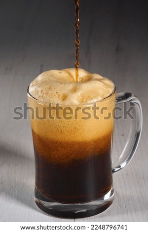 Pouring brown beer in a glass half a litre mug