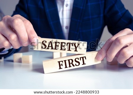 Closeup on businessman holding a wooden block with "Safety first", Business concept