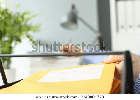 Person writes personal address in handwriting and takes yellow envelope with mail