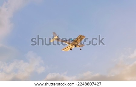A light plane flying through the clouds at sunset Royalty-Free Stock Photo #2248807427