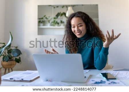 Asian businesswoman on a video call while sitting at her desk.Cropped shot of an attractive young woman using her laptop to make a video call at home