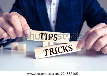 Closeup on businessman holding a wooden block with "Tips And Tricks", Business concept