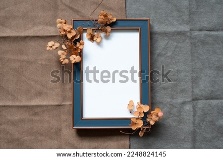 Picture frame and hydrangea flower on brown and gray fabric background. top view, copy space