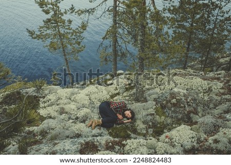 Nature healing scenic photography. Picture of traveler curling up on mountain cliff with evergreen trees on background. High quality wallpaper. Photo concept for ads, travel blog, magazine, article