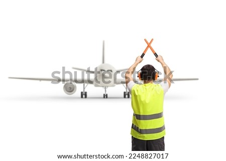 Rear view shot of a marshaller signalling with crossed wands in front of an aircraft isolated on white background
