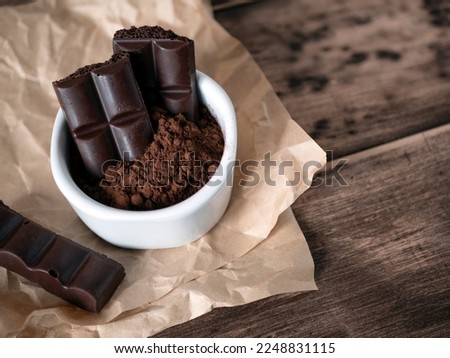 Dark porous chocolate pieces and cocoa powder on the wooden background. Bitter aerated chocolate, selective focus Royalty-Free Stock Photo #2248831115