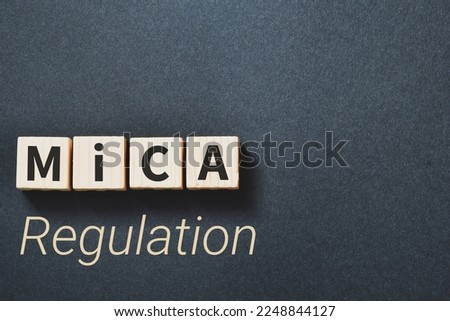 Markets in Crypto-Assets (MiCA) Regulation inscription on wooden blocks on dark background.