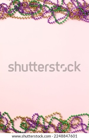 Frame of Mardi Gras beads on pink background. Greeting card template, poster, vertical banner design.