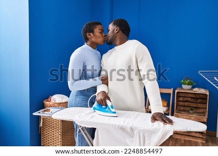 Man and woman couple ironing clothes kissing at laundry room