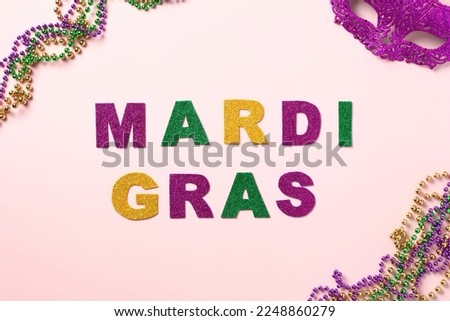 Mardi Gras background. Mardi gras lettering with carnival mask and beads on pink background.