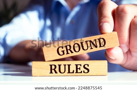 Closeup on businessman holding a wooden block with "GROUND RULES" Business concept