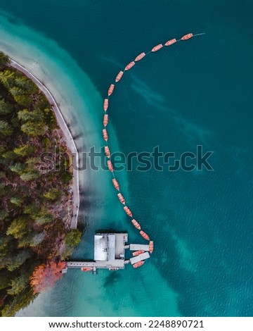 Top down aerial view of the famous Lago di Braies and its turquoise waters and lined-up row boats, Italian Dolomites, South Tyrol - boathouse - Alto Adige - Pragser Wildsee, Val Pusteria Royalty-Free Stock Photo #2248890721