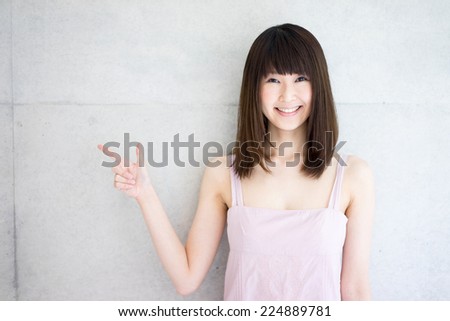 young woman showing against concrete wall 