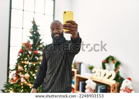 Young african american man make selfie by the smartphone standing by christmas tree at home