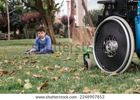 Child with disability sitting on the grass in a park.