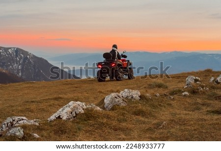 A rider riding quad bike atv off road on the mountain at sunset adventure travel.