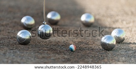 Magnetic pick-up tool for petanque. Petanque balls boules bowls on closeup on sand gravel court background, lifting the ball with a magnet Royalty-Free Stock Photo #2248948365