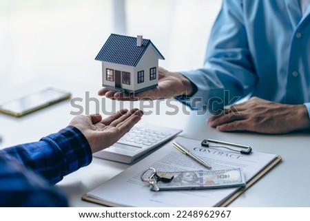 House purchase concept, real estate agent with house model talking to client about buying home insurance and client signing contract under formal contract agreement with real estate law