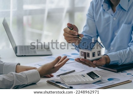 House purchase concept, real estate agent with house model talking to client about buying home insurance and client signing contract under formal contract agreement with real estate law Royalty-Free Stock Photo #2248962971