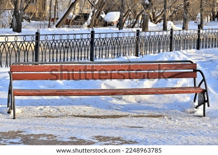 An empty bench in the city square on a winter day