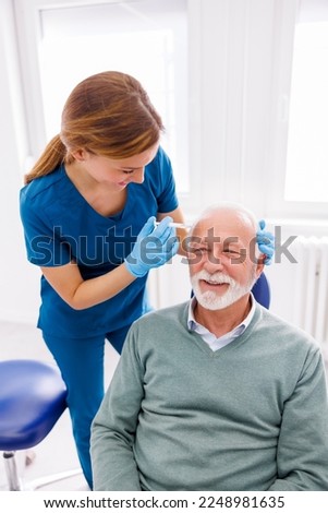 Doctor applying dermal fillers to senior male patient; senior man getting hyaluronic acid or botox anti-age treatment