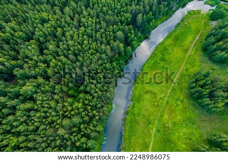 drone view of a river bend in a forest area, the banks are covered with grass. landscape view from a drone to a forest area. natural view of the river and the road by the river