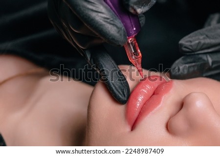 Permanent lip makeup. Microblading lip tattoo with special coloring pigment corrects lip color in cosmetology clinic. Extreme close-up. Royalty-Free Stock Photo #2248987409