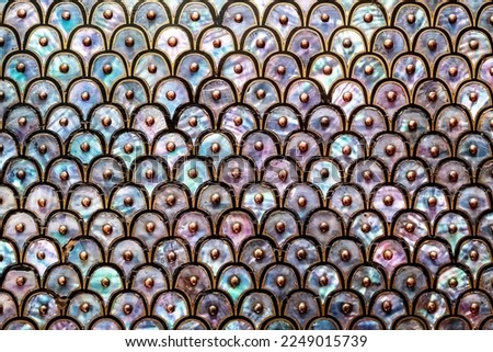 Abstract background of mother of pearl. Circular and overlapping antique design of nacre or abalone shell, with black and gold design and studs.