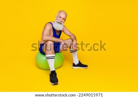 Full body photo of positive sportive person sitting fit ball enjoy dynamic workout isolated on yellow color background