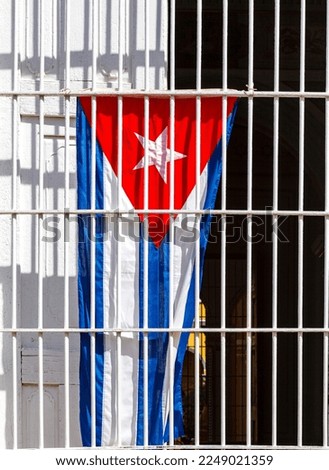 Cuban flag behind white bars in Trinidad, Cuba, Caribbean