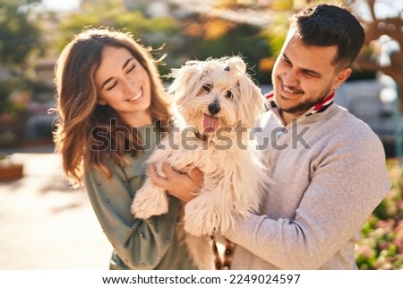 Man and woman holding dog standing together at street