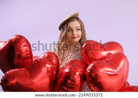 Beautiful young woman with heart-shaped balloons on lilac background. Valentine's Day celebration