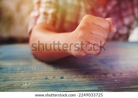 A man fist in anger on wood table with soft light, concept as fighting of business to success