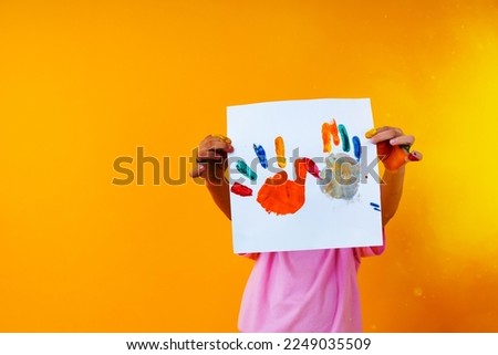 young kid holding paper art on yellow background